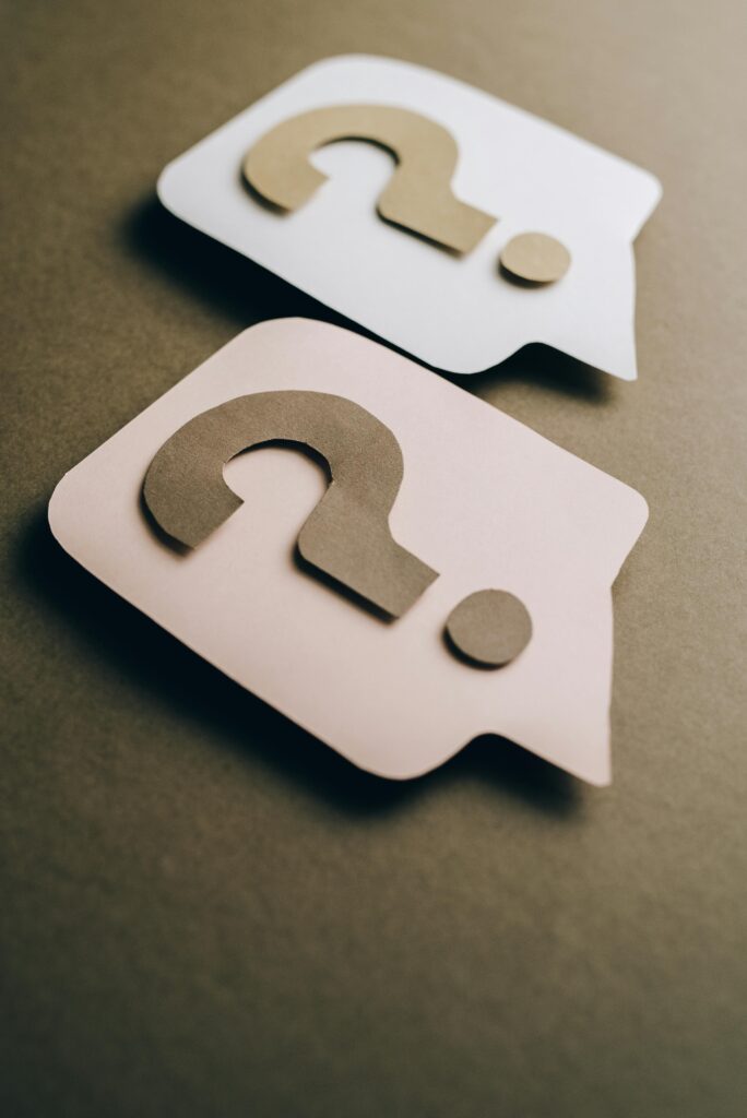 Two paper craft question marks on speech bubbles create a conceptual visual.